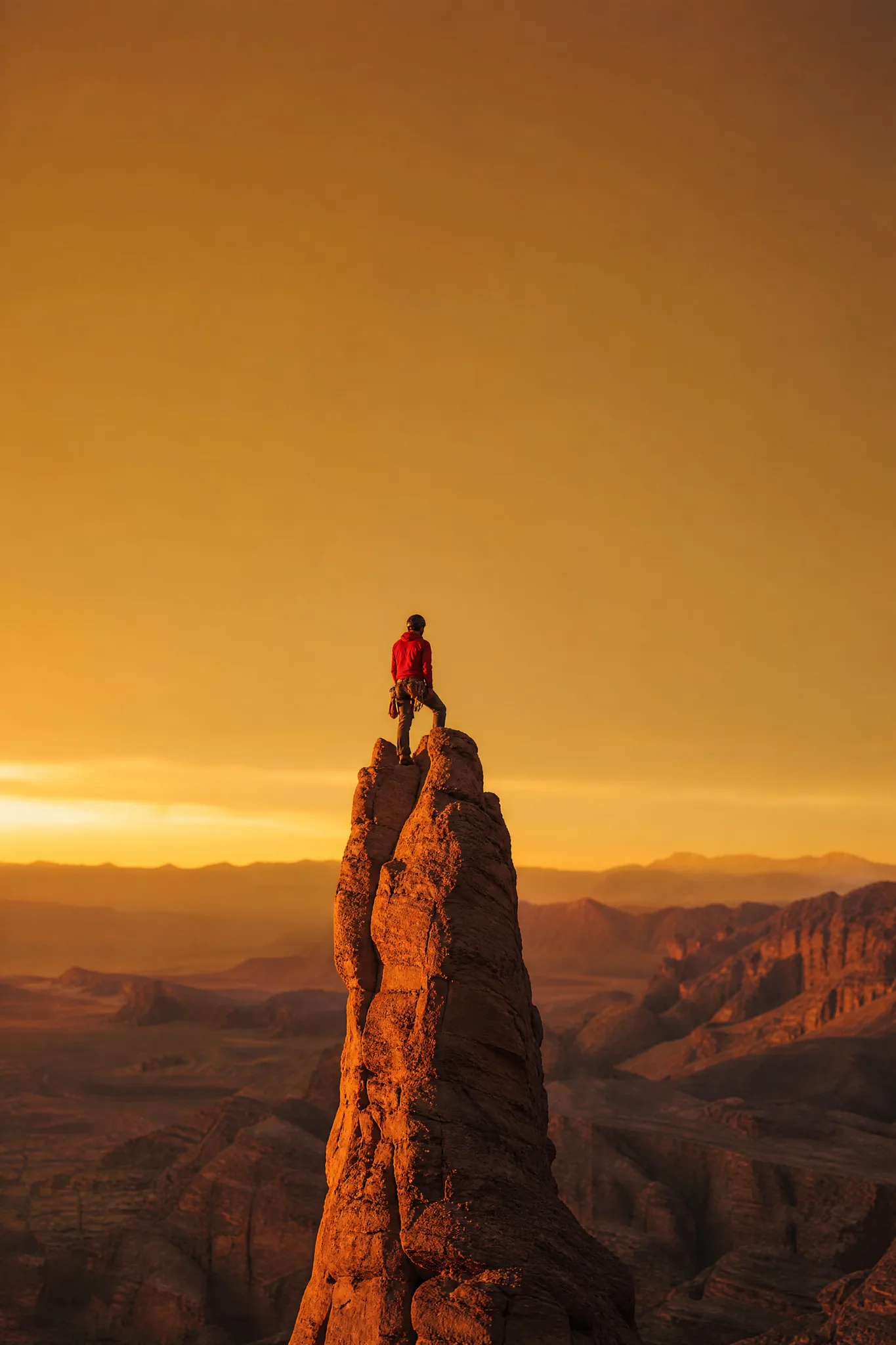 Grok Imagine Image: Summit with Open Sky Climber in a red jacket standing on top of a narrow sandstone tower under a wide open sky